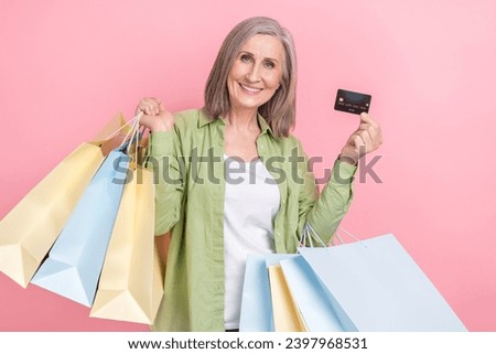 Photo of charming grey white hair grandmother wear green stylish clothes hold packages plastic card isolated on pink color background