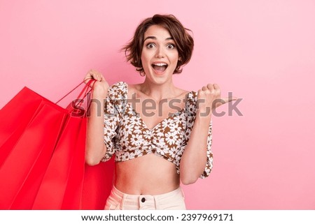 Photo of astonished pretty slim person hold mall bags open mouth indicate finger empty space isolated on pink color background