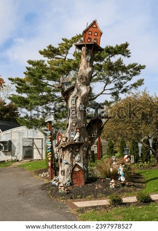 A tree with a house on top of it decorated to look like a trolls or gnomes village.
