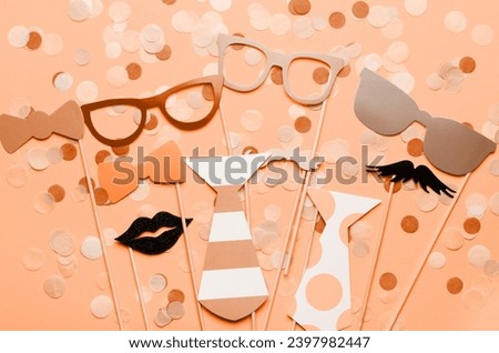 Photo booth props glasses, mustache, lips on a pink background flat lay. Birthday parties and weddings. New trending PANTONE 13-1023 Peach Fuzz colour of 2024 year 