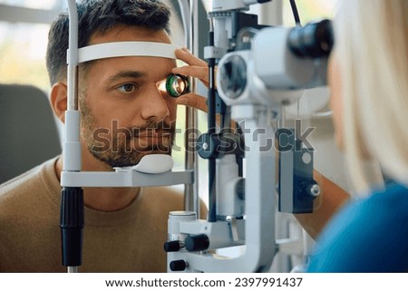 Young man having his eyes checked during a visit at oculist's office. Royalty-Free Stock Photo #2397991437