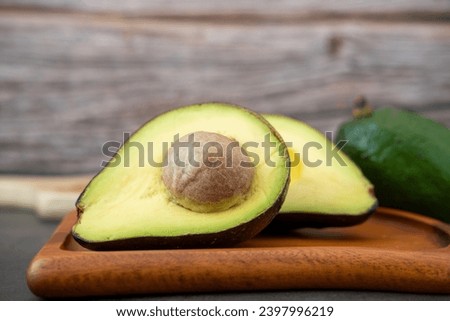 Close-up of a halved avocado on a wooden plate.