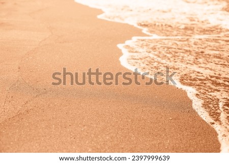 Wave of the pure sea on the sandy beach. Demonstrating color of 2024 year - peach.