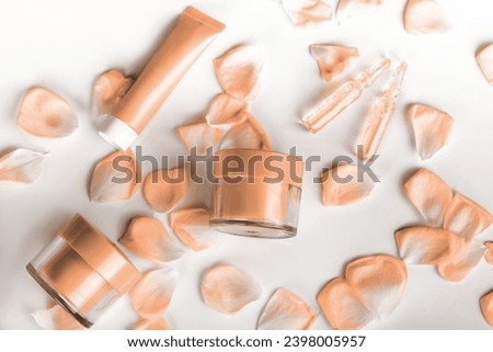 empty tubes of cream on a white background with flowers. New trending PANTONE 13-1023 Peach Fuzz colour of 2024 year 