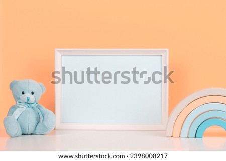 White blank horizontal wooden frame mockup, baby room art, empty wood blank frame with baby kid toys on white desk and peach pink background. Front view. Early education, kindergarten background