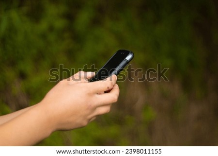 Businesswoman using cell phone, hand holding phone with blur background, browsing internet with cellular device