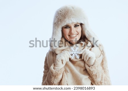smiling modern woman in winter coat and fur hat isolated on white background in white gloves with snowflake.