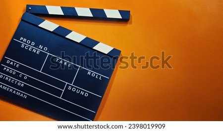 A clapperboard with an orange background. Symbol of filmmaking and video production. Professional type of equipment, used on films to assist in synchronizing of picture and sound