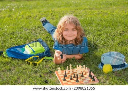Little kid chessman play chess game, checkmate. Child playing chess in spring park. Royalty-Free Stock Photo #2398021355