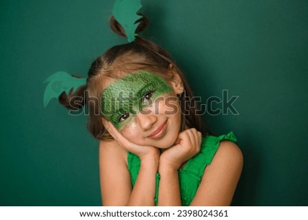 A cute beautiful girl with makeup with a painted dragon and gold sequins on her cheeks. A headdress in the shape of green dragon wings. New Year 2024