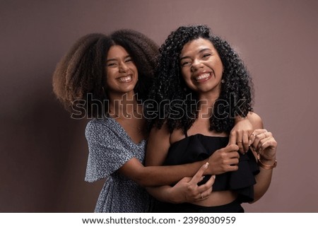 Two young friends together, hugging, posing for a photo. Friendship on the rise. Isolated on salmon-colored background.