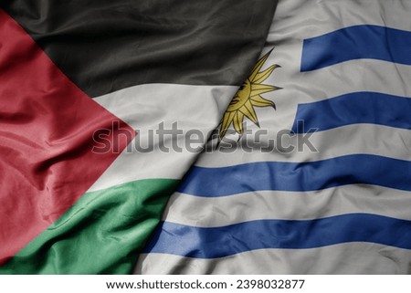 big waving national colorful flag of uruguay and national flag of palestine . macro