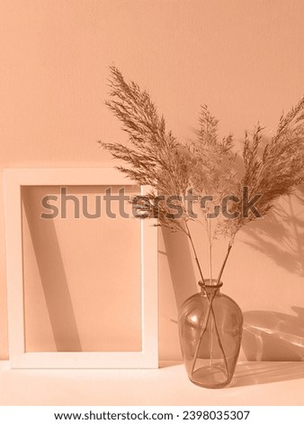 Peach fuzz is the color of the year 2024. Frame, glass vase and dry flowers toned in fashion blended pink-orange trend-setting colour of year Peach Fuzz Royalty-Free Stock Photo #2398035307