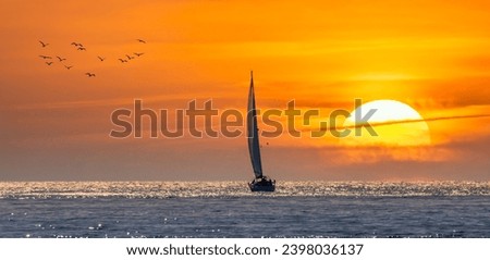 Silhouette of a sailboat sailing towards the sun at sunset