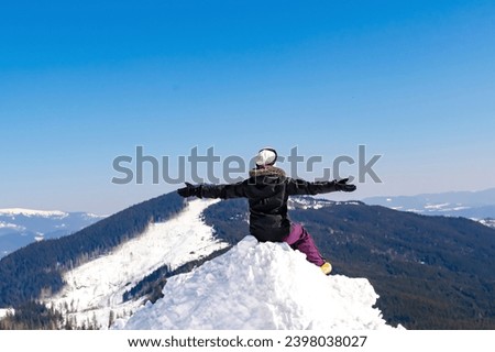 Women alpine girl in winter overalls sitting on snow hill looking at high Carpathian mountains at winter ski resort holiday, outdoor nature landscape, Ukraine, Europe.aerial view. Royalty-Free Stock Photo #2398038027