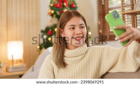 Winter season concept, Women taking selfie on smartphone while sitting on couch near christmas tree.