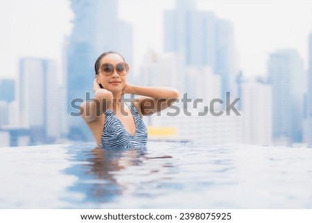 Portrait beautiful young asian woman relax smile enjoy leisure around outdoor swimming pool with city view