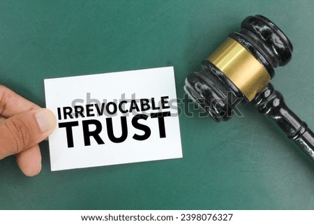 judge's gavel and hand holding colored paper with the word Irrevocable trust. the concept of trust Royalty-Free Stock Photo #2398076327