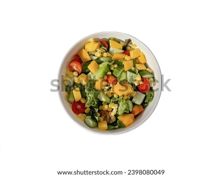 The white background in the picture is a salad bowl with vegetables such as green vegetables, cucumbers, tomatoes, boiled corn, boiled pumpkins, all cut and ready to eat, mixed together in a salad 