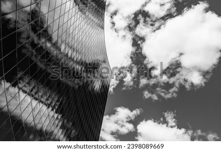 Couds they are a mergin - Black and white photo of a building with glass facade which clouds merging in the reflection