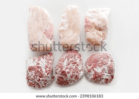 Frozen chicken breast and minced beef in food plastic wrap or cling film. Photo can be used for how to wrap meat for freezer concept.