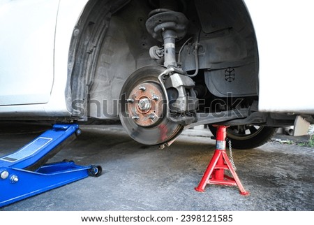 Car brake discs without wheels , Lift the car with the hydraulic car jack and jack stand in the car repair shop to repair the brake system Royalty-Free Stock Photo #2398121585