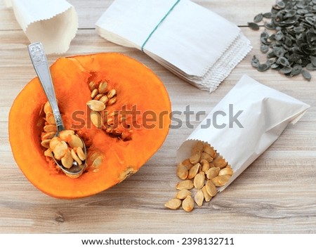 Getting own seeds from orange hokaido pumpkin. Dried seeds in paper bag, seeds from oil pumpkin behind. High angle view.