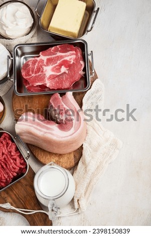 Saturated fats on tables. Raw meat, sausages, cheese, butter. Bad food concept. Top view, copy space. Royalty-Free Stock Photo #2398150839