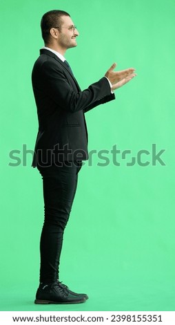 young man in full growth. isolated on green background demonstrates with hands