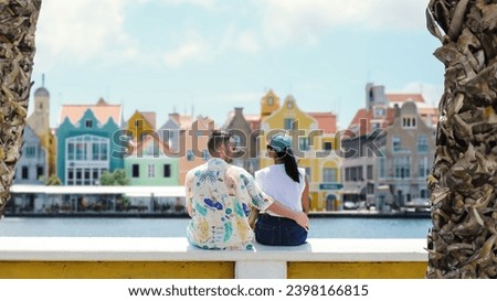 Willemstad Curacao has colorful buildings around Willemstad Punda and Otrobanda, multicolored homes on Curacao Caribean Island, couple of caucasian men and Asian women on vacation in Curacao. Royalty-Free Stock Photo #2398166815