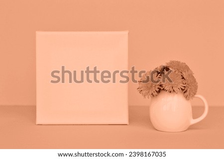 Dandelion bouquet in a vase and picture frame on a blue background. Peach fuzz is color of year 2024 tinted image