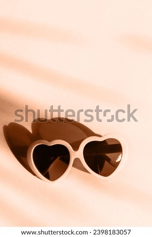 Trendy Peach Fuzz pantone color of Year 2024 background. Heart sunglasses on bright light peach background