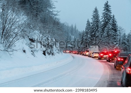 A line of cars on a snow-covered road. Long wait in line after a car accident. Royalty-Free Stock Photo #2398183495