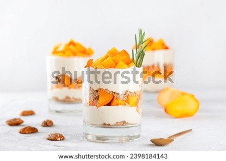 Parfait with persimmon, rosemary, pecan, whipped coconut cream and biscuit. Vegan, sugar, gluten and lactose free. Fruit dessert, cheesecake, trifle, mouse in a glass. Royalty-Free Stock Photo #2398184143
