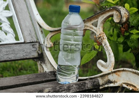 Water plastic bottle on dark brown wooden chair. Discipline to keep public park clean by drop in the bin.