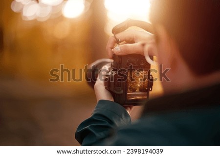Isolated Close-up of a man holding a modern photo camera while looking at the screen. Horizontal banner image of camera using with the screen visible. Concept of an amateur taking photos in the forest