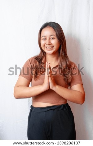 Young smiling Asian woman gesturing traditional greeting isolated on white background