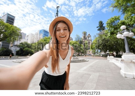 Beautiful traveler girl takes self portrait in Porto Alegre, Brazil. Young tourist woman visiting Praca da Matriz square in Porto Alegre, Rio Grande do Sul, Brazil. Royalty-Free Stock Photo #2398212723