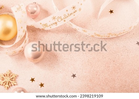 Festive Christmas and New Year background with gold and pink baubles, ribbons and stars. White ribbon with Merry Christmas written.