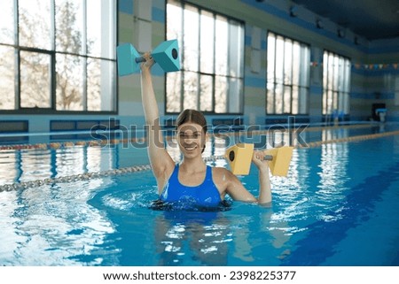 Young female doing aerobic workout in swimming pool Royalty-Free Stock Photo #2398225377