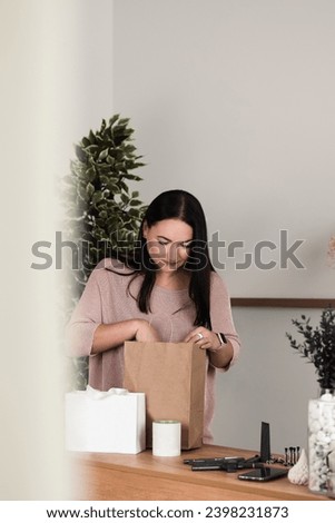 A brunette girl is standing at a desk in the office with a paper bag and cosmetics