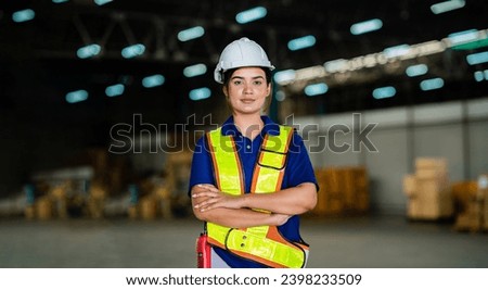 Happy female factory manager in warehouse while standing on shelves. looking at camera