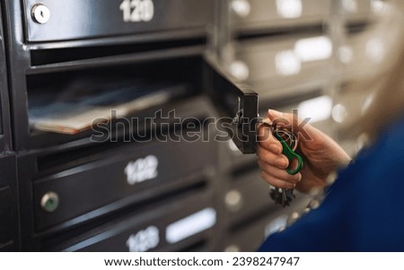 Woman checking mailbox in apartment building. Royalty-Free Stock Photo #2398247947