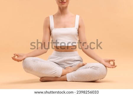 Woman practicing yoga on beige background, closeup. Lotus pose
