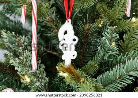 A candy cane shaped ornament hung on the Christmas tree.