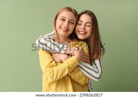Beautiful young woman hugging her happy mother on green background. International Hug Day Royalty-Free Stock Photo #2398262817