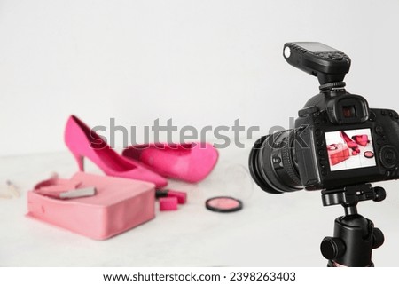 Fashionable shoes, bag and cosmetics on display of professional photo camera in studio