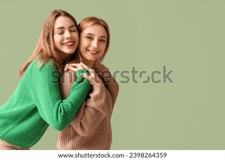 Happy young woman hugging her mother on green background. International Hug Day Royalty-Free Stock Photo #2398264359