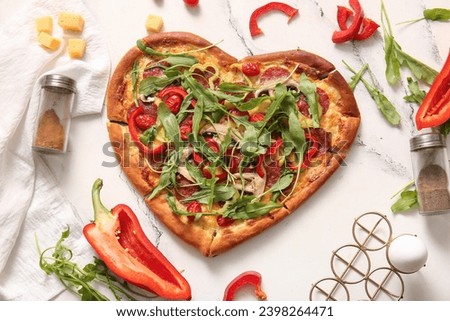 Tasty heart shaped pizza and ingredients on white background