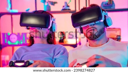 Gamers play in a room with RGB lighting. Game with vr glasses. Joystick game. Handsome guy and girl play computer games. Virtual reality glasses.
